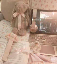 a laptop computer sitting on top of a bed next to a stuffed animal