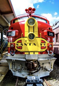 a red and yellow train sitting on the tracks