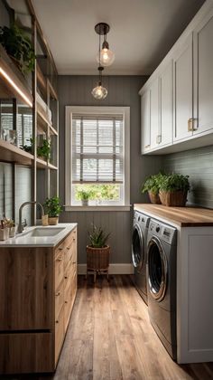 a washer and dryer in a small room with wooden floors, white cabinets and gray walls