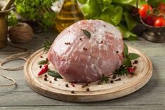 raw meat sitting on top of a cutting board surrounded by vegetables and spices in the background