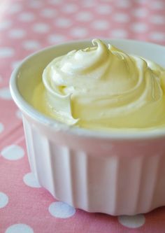 a white bowl filled with cream on top of a pink table