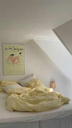 an unmade bed with yellow sheets and blankets on top of it in a loft