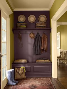 an entryway with coat racks, baskets and coats hanging on the wall next to it