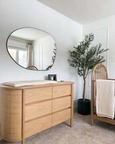 a large mirror hanging over a dresser next to a baby crib