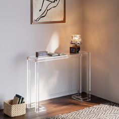 a clear console table with books and magazines on it in front of a framed painting