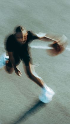 a blurry image of a man playing basketball on the court with his shoes off