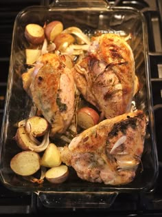 chicken, potatoes and onions in a glass dish on an oven burner with tongs