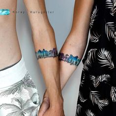 two people holding hands with tattoos on their arms