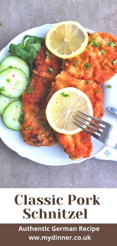 a white plate topped with chicken and cucumbers next to a fork on top of a table