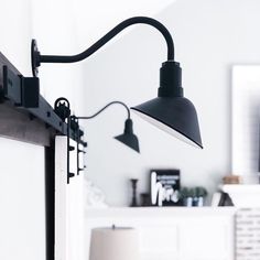 a black lamp is hanging from the side of a wall in a room with white walls