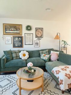 a living room with green couches and pictures on the wall above it's coffee table