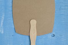 a wooden spatula sitting on top of a piece of brown paper next to a blue background