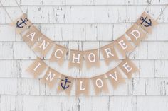 an anchor and love banner hanging on the side of a white building with wood planks