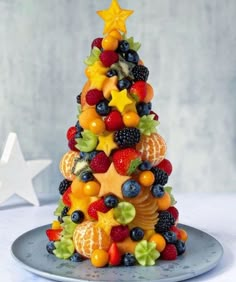 a christmas tree made out of fruits on a plate with star decoration in the background