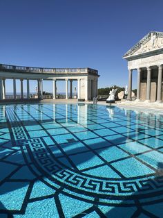 an empty swimming pool with columns and pillars in the background