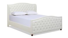 a white bed with an upholstered headboard and pillows on top of it