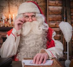 a man dressed as santa claus sitting at a table with a piece of paper in front of him