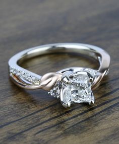 a white gold ring with a princess cut diamond in the center on a wooden surface