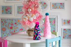 a pink christmas tree sitting on top of a table next to a vase filled with balls