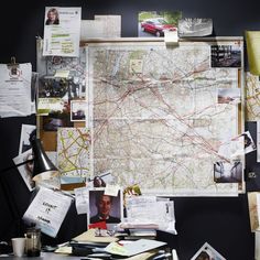 a map is hanging on the wall next to a desk with papers and other items