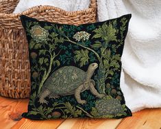 a decorative pillow with an image of a turtle and flowers on it, next to a wicker basket