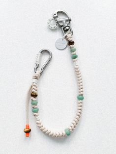 a white bracelet with green and orange beads