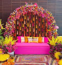 a pink couch sitting in front of a flower covered wall with lots of flowers on it