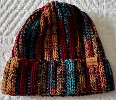 a multicolored knitted beanie sits on a bed