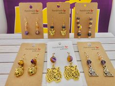 (Beginning with top left to right) 1.  Rain Flower bead with amber crystal with  gold plated ear wires. Total length 24mm, Drop 18mm and the   width is 8mm. 2.  Tiger head charm with purple crystal, on gold plated ear wires. 30mm drop earrings. 3.  Kidney wire Drop earrings, with Purple and gold crystals. Total length 50mm, drop length 20mm, and    the width is 8mm. 4.  Tiger head charm with 10mm metallic purple/gold beads.  35mm drop earrings. 5.   Large Tiger head with Purple/Gold Agate beads. Amber Beaded Earrings For Gift, Gold Round Beads Earrings For Gift, Adjustable Gold Wire Wrapped Crystal Earrings, Gold Wire Wrapped Adjustable Crystal Earrings, Adjustable Gold Crystal Earrings Nickel Free, Gold Nickel-free Round Beaded Crystal Earrings, Gold Crystal Earrings Nickel Free Round Beads, Gold Crystal Earrings With Nickel-free Round Beads, Gold Wire Wrapped Crystal Earrings As Gift