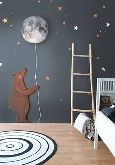 a child's room with a teddy bear and moon wall decal on the wall