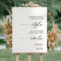 a white sign sitting on top of a wooden easel in front of a lush green field