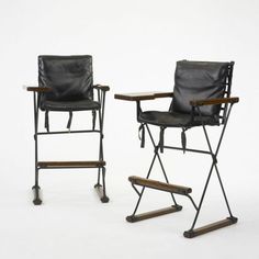 two black leather folding chairs and a wooden table on casteors against a white background