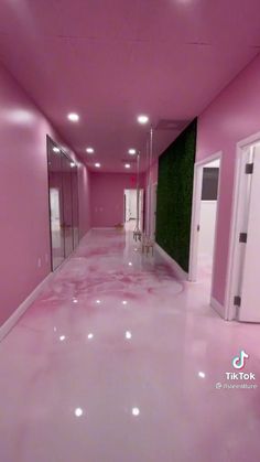 an empty hallway with pink walls and flooring in the center is lit by recessed lights