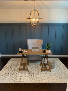 a desk with a laptop on top of it in front of a blue paneled wall