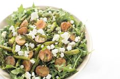 a salad with asparagus, mushrooms and feta cheese in a white bowl