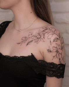 a woman wearing a black top with flowers on her chest and shoulder tattoo design in the middle