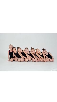 a group of young ballerinas posing for a photo in front of a white background