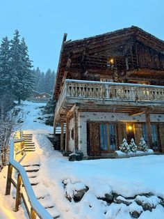 a snow covered house with stairs leading up to it and trees in the background at night