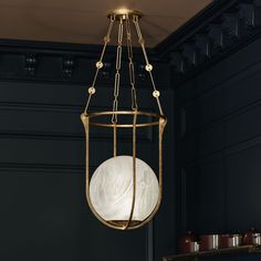 a light fixture hanging from the ceiling in a room with dark walls and gold fixtures