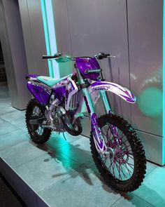 a purple dirt bike parked next to a wall