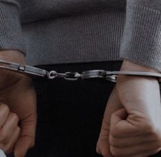 a person with their hands chained to the back of his pants and holding onto some metal chains