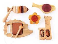 various wooden toys are arranged on a white surface, including spoons and spatulas