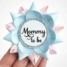 a hand holding a blue and pink bow with the words mommy to be on it