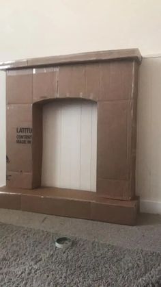 an empty cardboard box sitting on the floor in front of a fire place and door