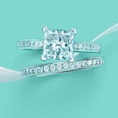 an engagement ring and wedding band with a princess cut diamond in the center on a blue background