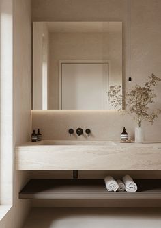 a bathroom sink with two towels on the counter and a vase filled with flowers next to it