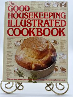 the good housekepping illustrated cookbook is displayed on a metal stand with an image of a pie in it