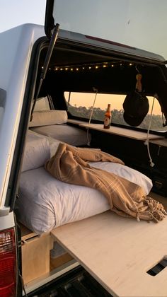 the back end of a truck with a bed and pillows in it's trunk