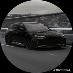 a black sports car driving down the road in front of a cityscape behind it