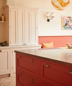 a kitchen with red cabinets and white cupboards on the wall, along with a breakfast nook